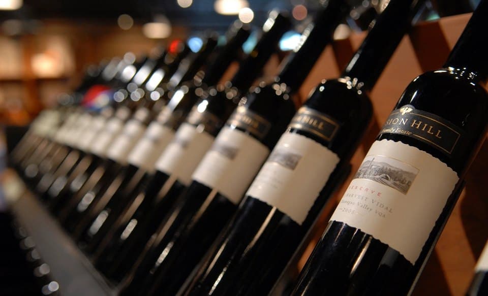 A row of dark bottles resting on a cellar shelf