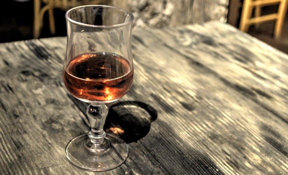 A single poured glass resting on a weathered wooden table